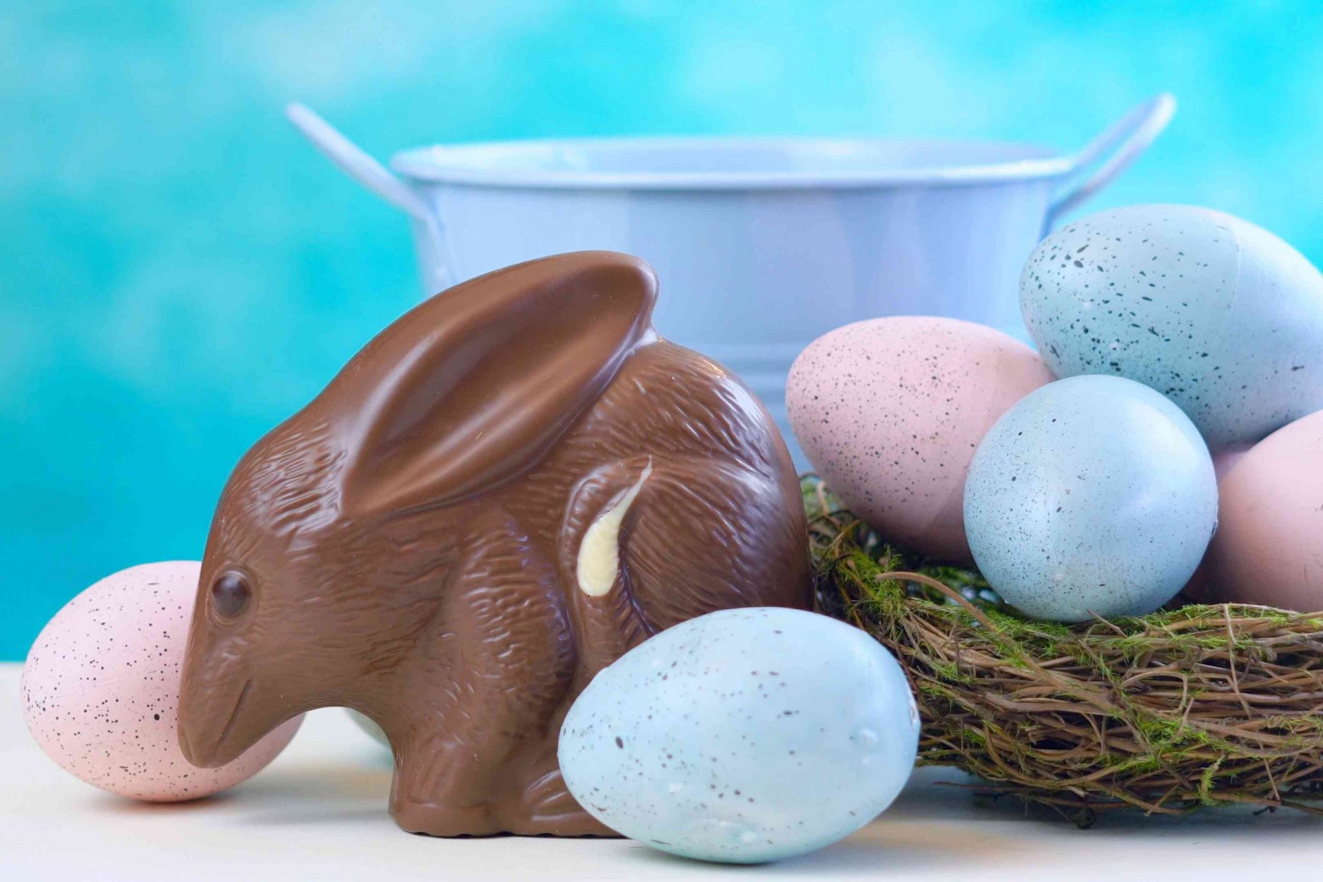 bilby de chocolate rodeado de huevos de Pascua de color pastel sobre un fondo azul brillante