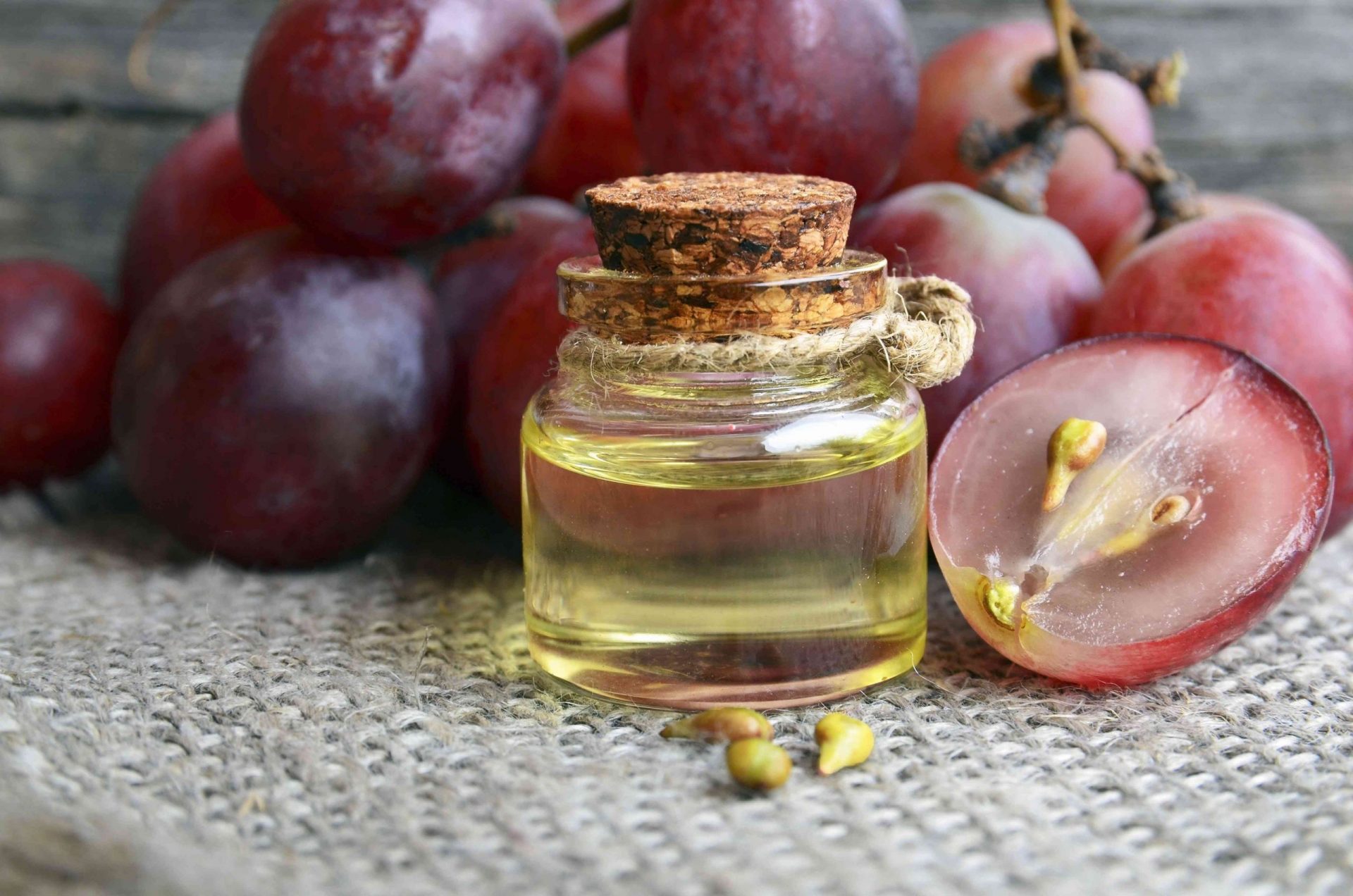 Botella de aceite de semilla de uva orgánico para el spa y el cuidado del cuerpo y bayas de uva frescas maduras sobre una vieja mesa de madera.Concepto de alimentos saludables,Bio,Productos ecológicos.