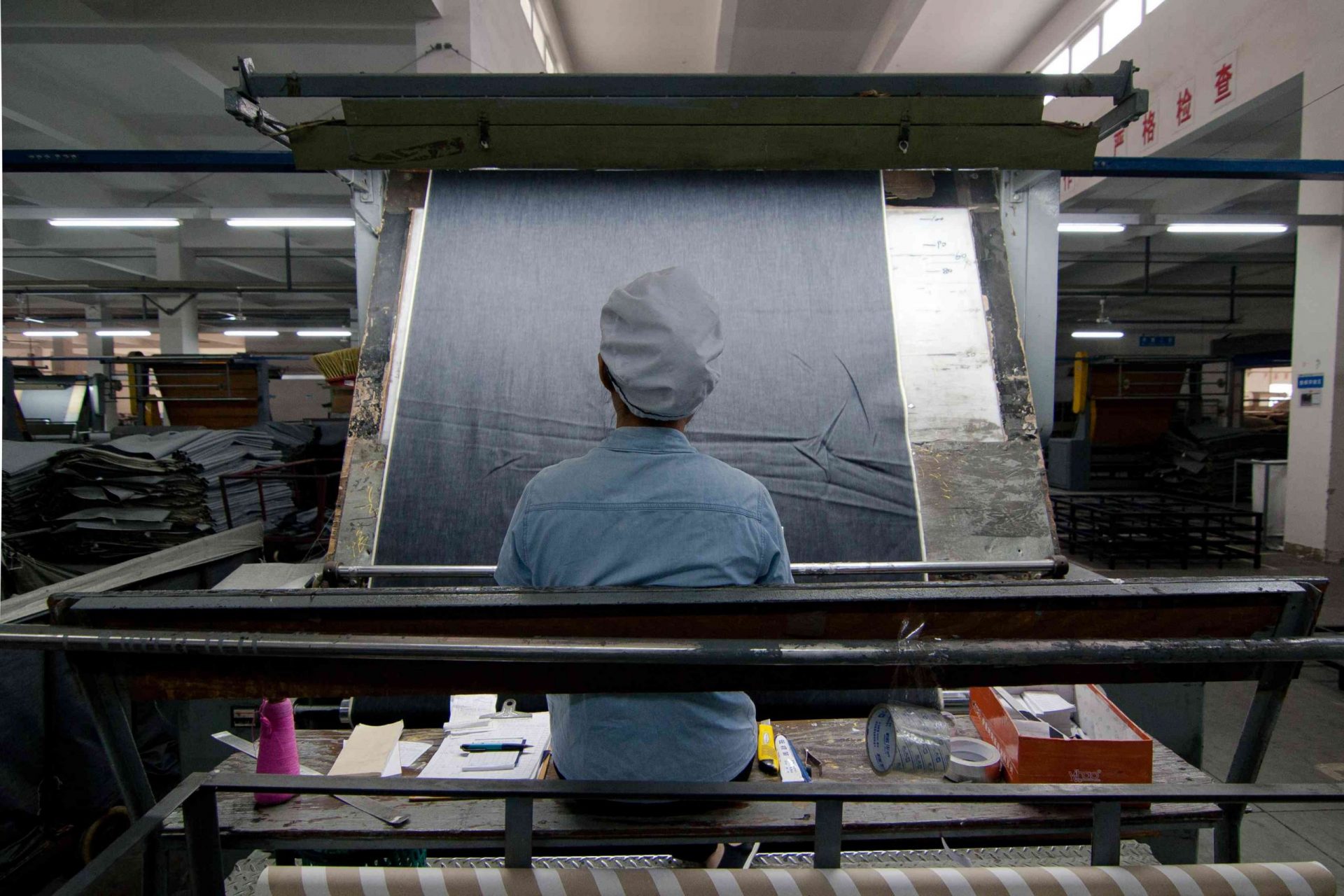 Un trabajador chino examina el tejido vaquero en una fábrica