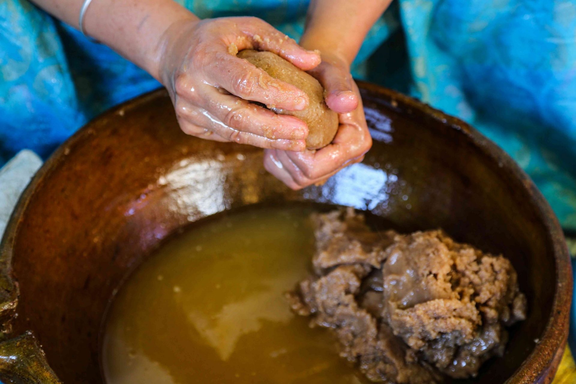 Primer plano de las manos de una mujer amazigh marroquí exprimiendo la pasta de argán