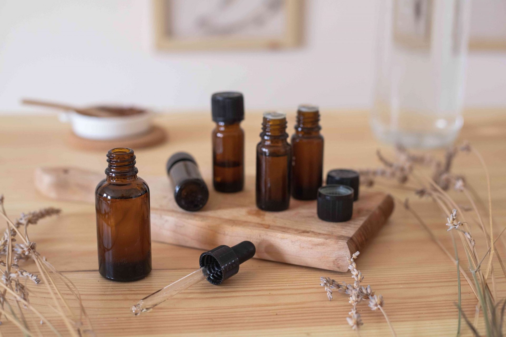 varios aceites esenciales en botellas de cristal marrón oscuro sobre una tabla de cortar de madera con lavanda seca