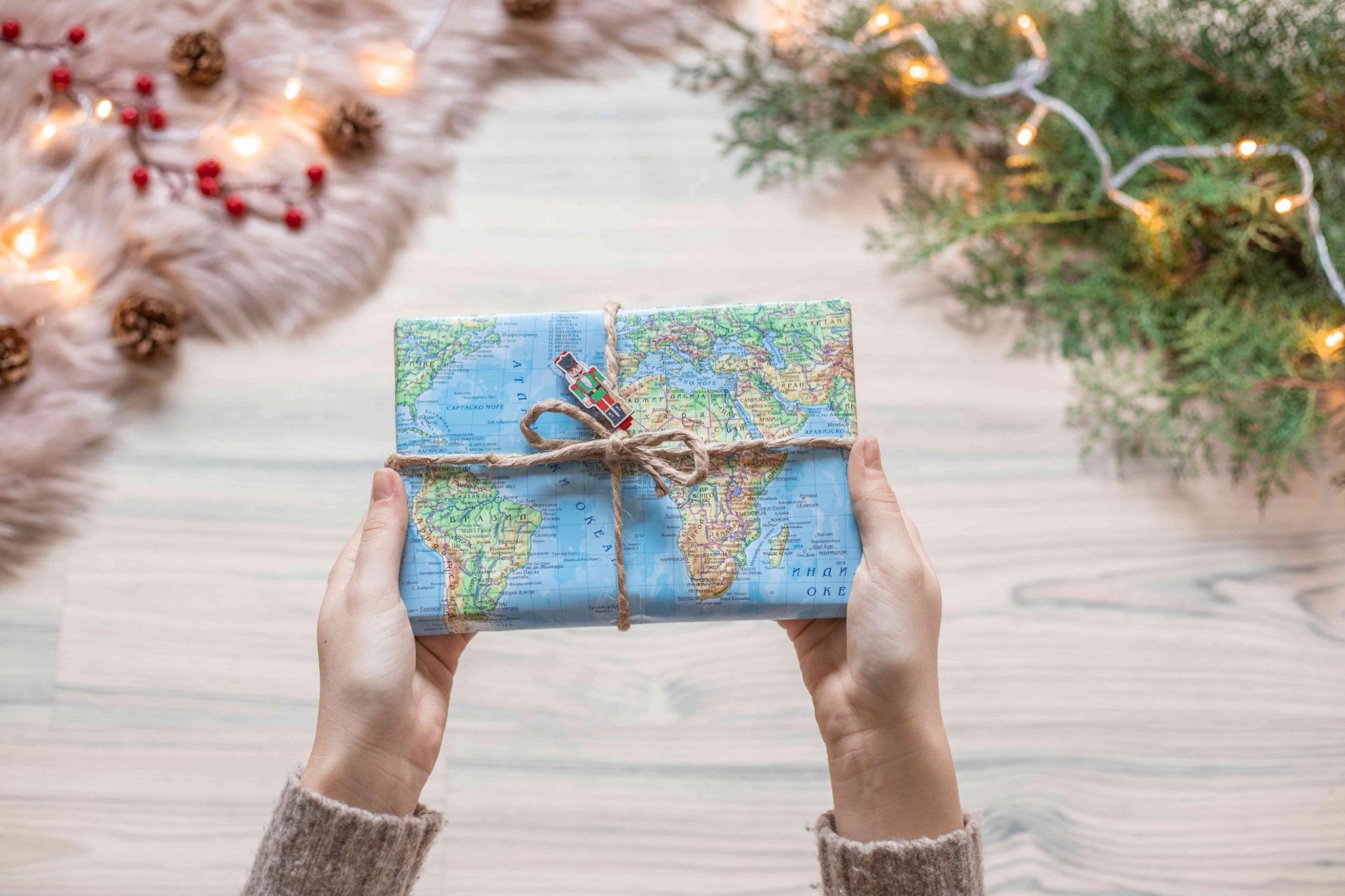manos sostienen un regalo de Navidad envuelto en un viejo mapa reciclado con cordel