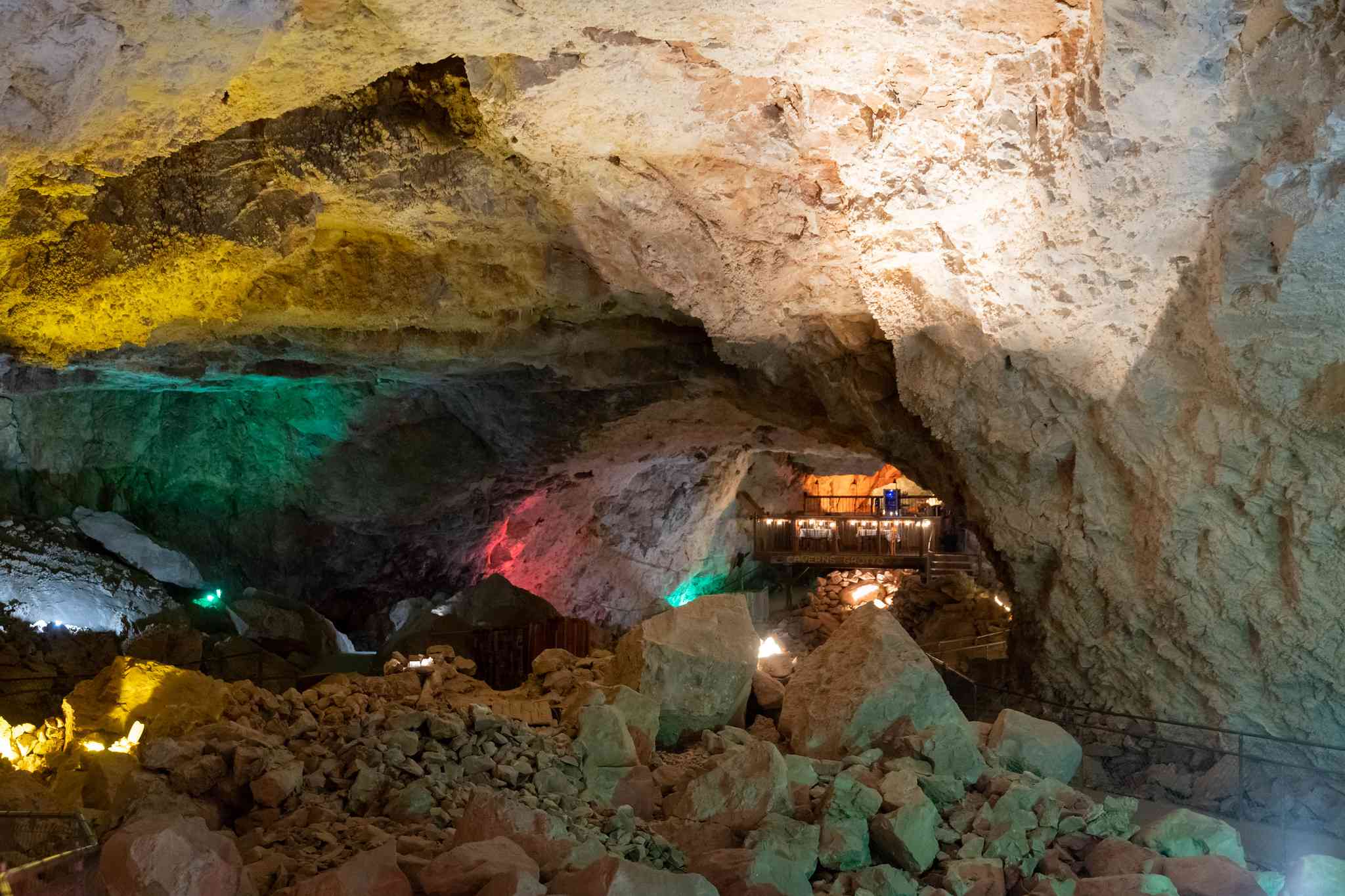 Luces multicolores y plataforma con mesas para comer dentro de la caverna