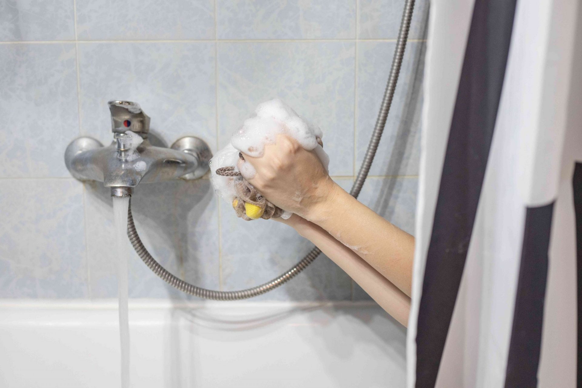 una persona se asoma a la bañera para hacer espuma de jabón con un estropajo