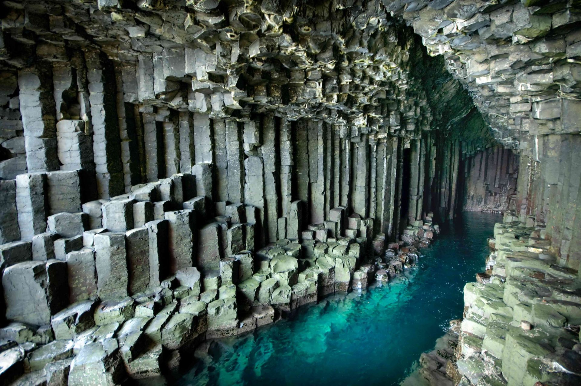 Columnas de basalto surgiendo del agua azul en la Cueva de Fingal
