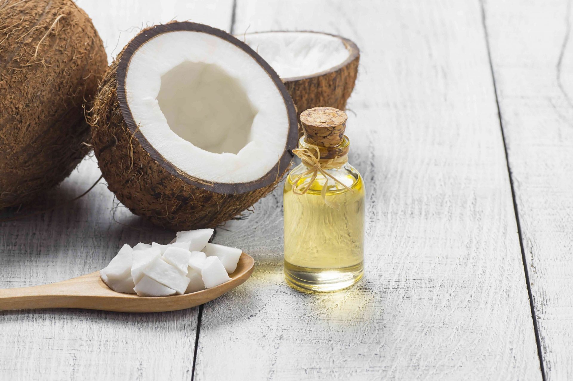 Botella de cristal de aceite de coco con fruta fresca de coco sobre fondo rústico, concepto de medicina terapéutica alternativa, Cocos nucifera