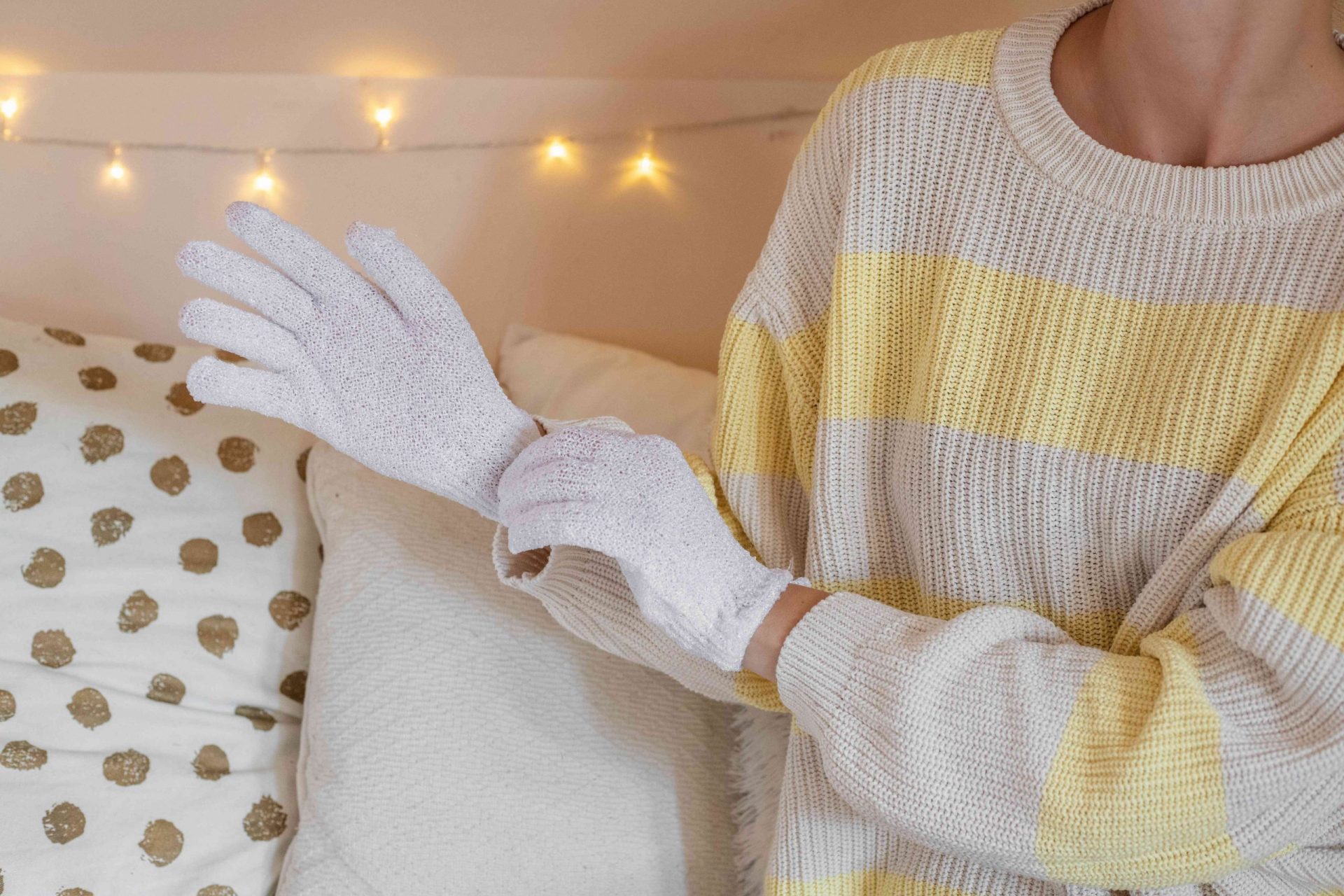una mujer se pone unos guantes blancos de algodón para retener la humedad antes de acostarse