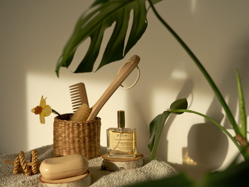 foto de naturaleza muerta de jabón en barra, accesorios de madera para el pelo y perfume con hoja de monstera