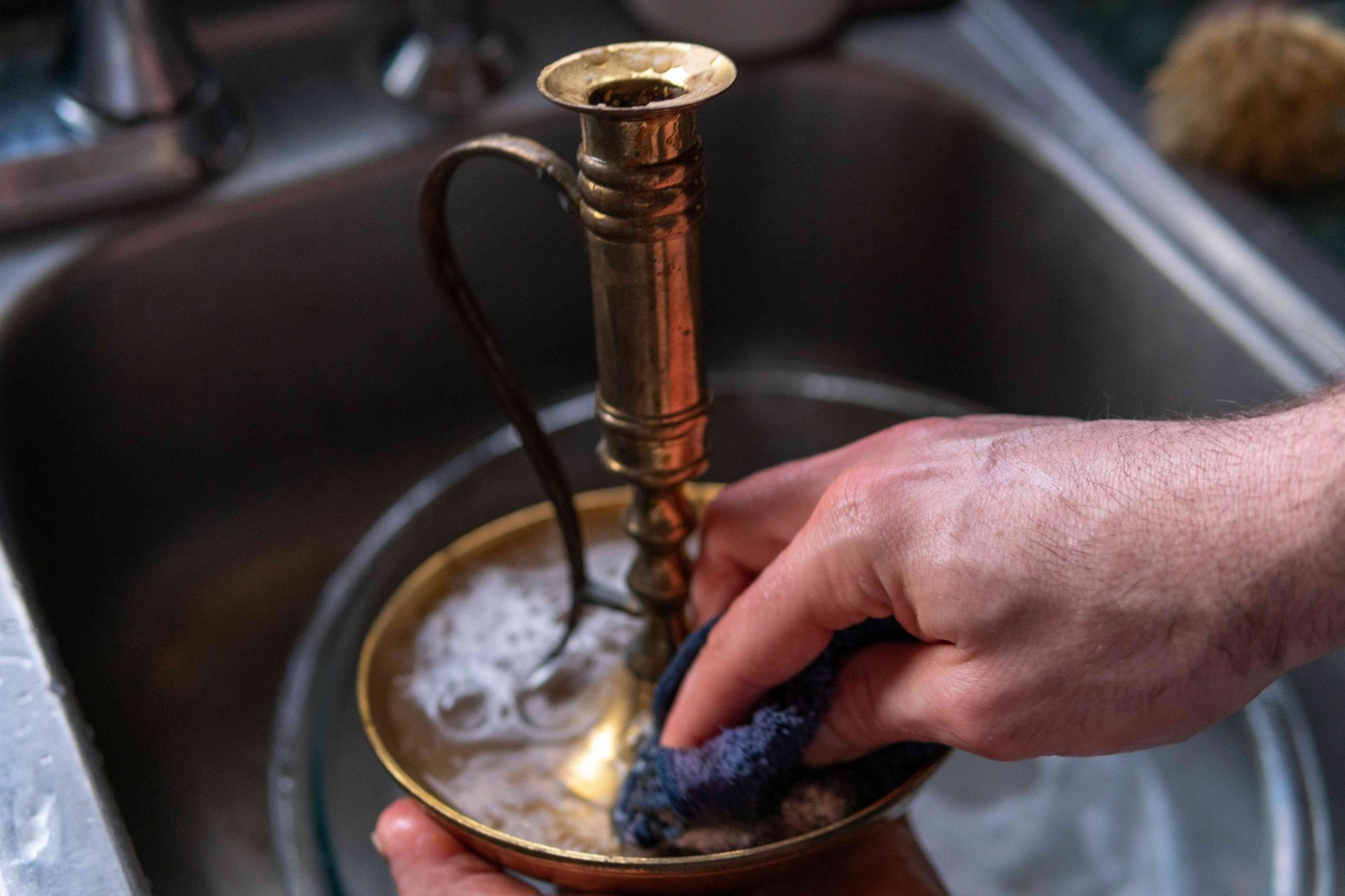 manos limpian el latón con agua y jabón