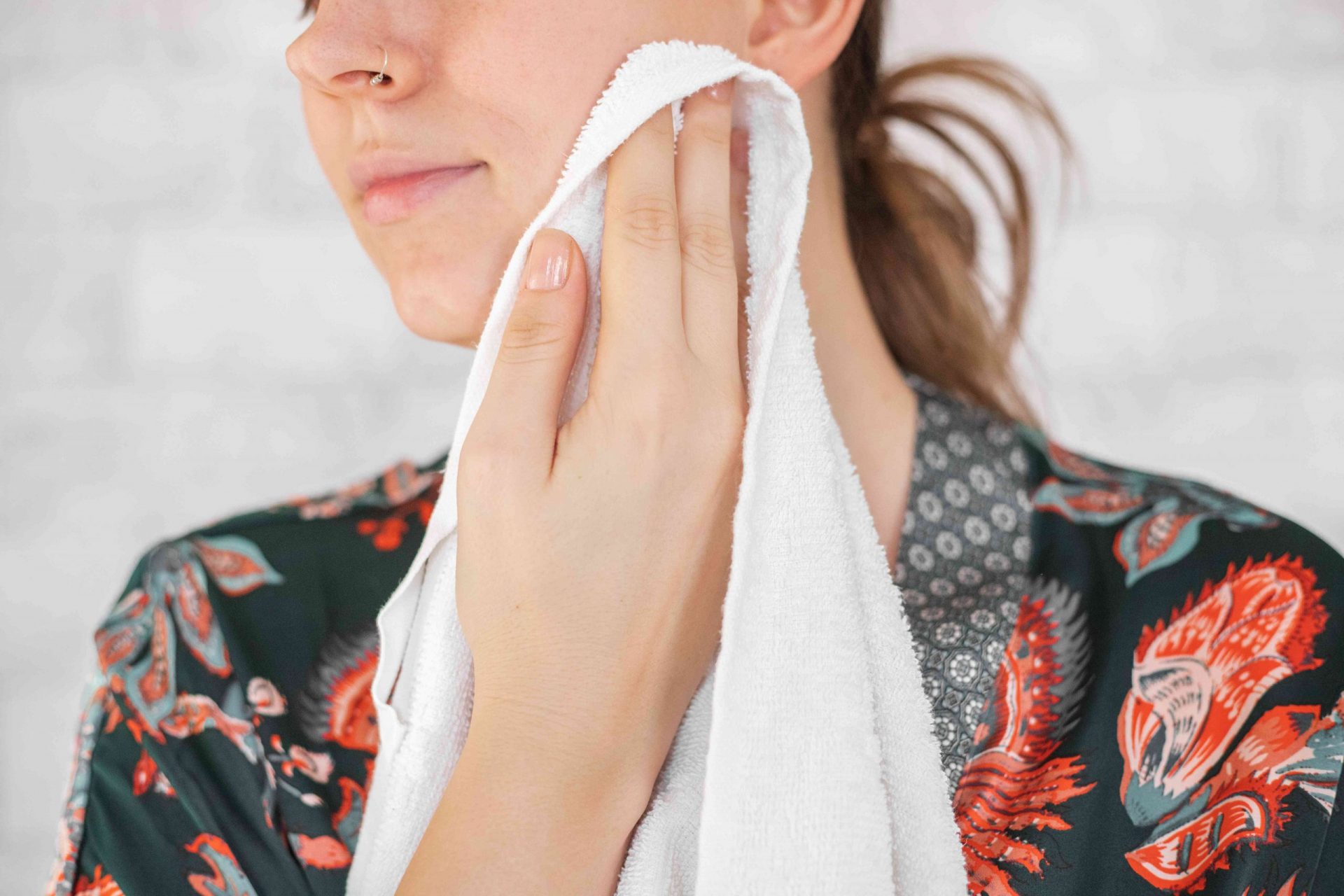 la mujer se seca la cara con una toalla blanca después de aplicarse la mascarilla de pepino diy