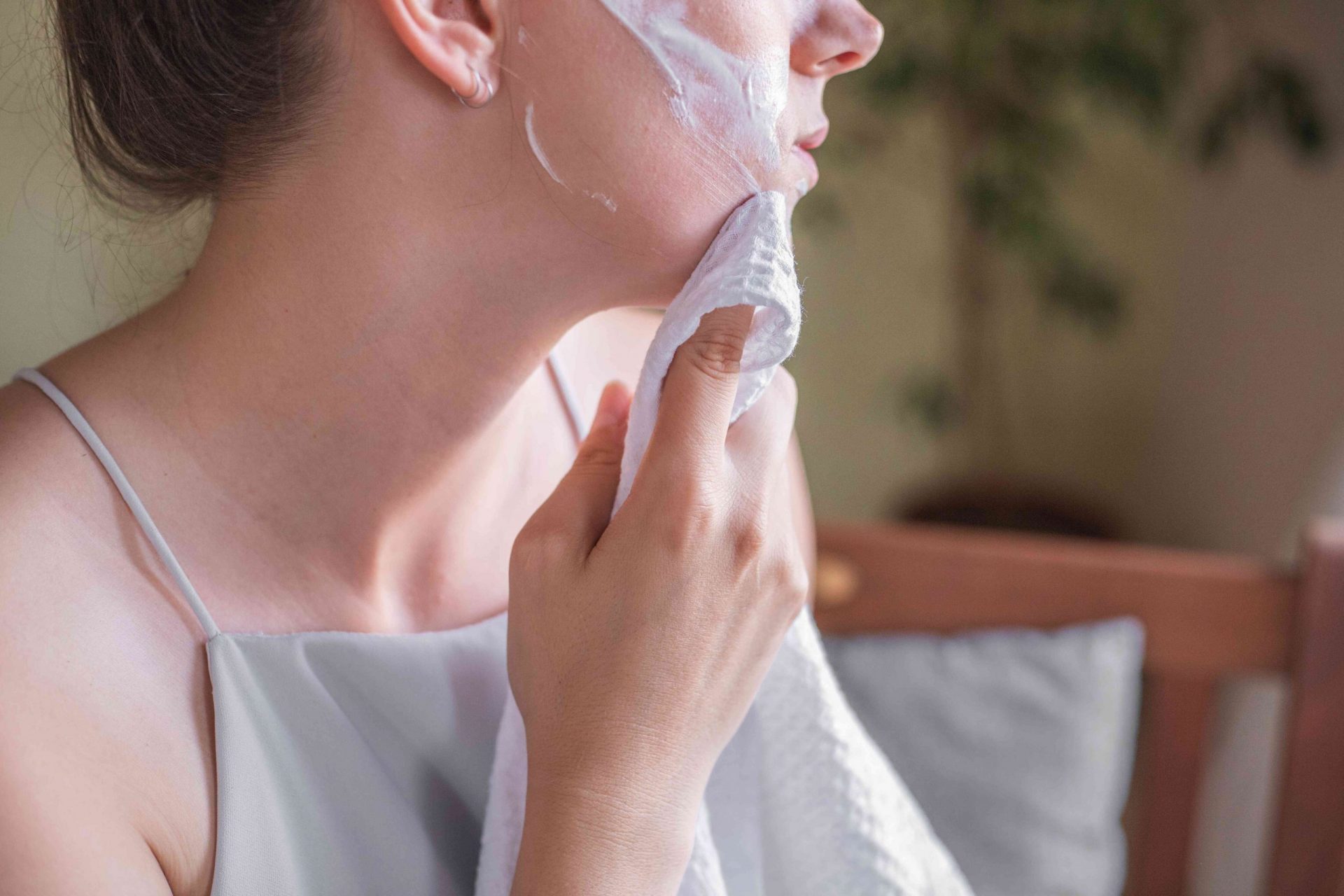 perfil lateral de una mujer limpiando la mascarilla casera de yogur con una toalla húmeda