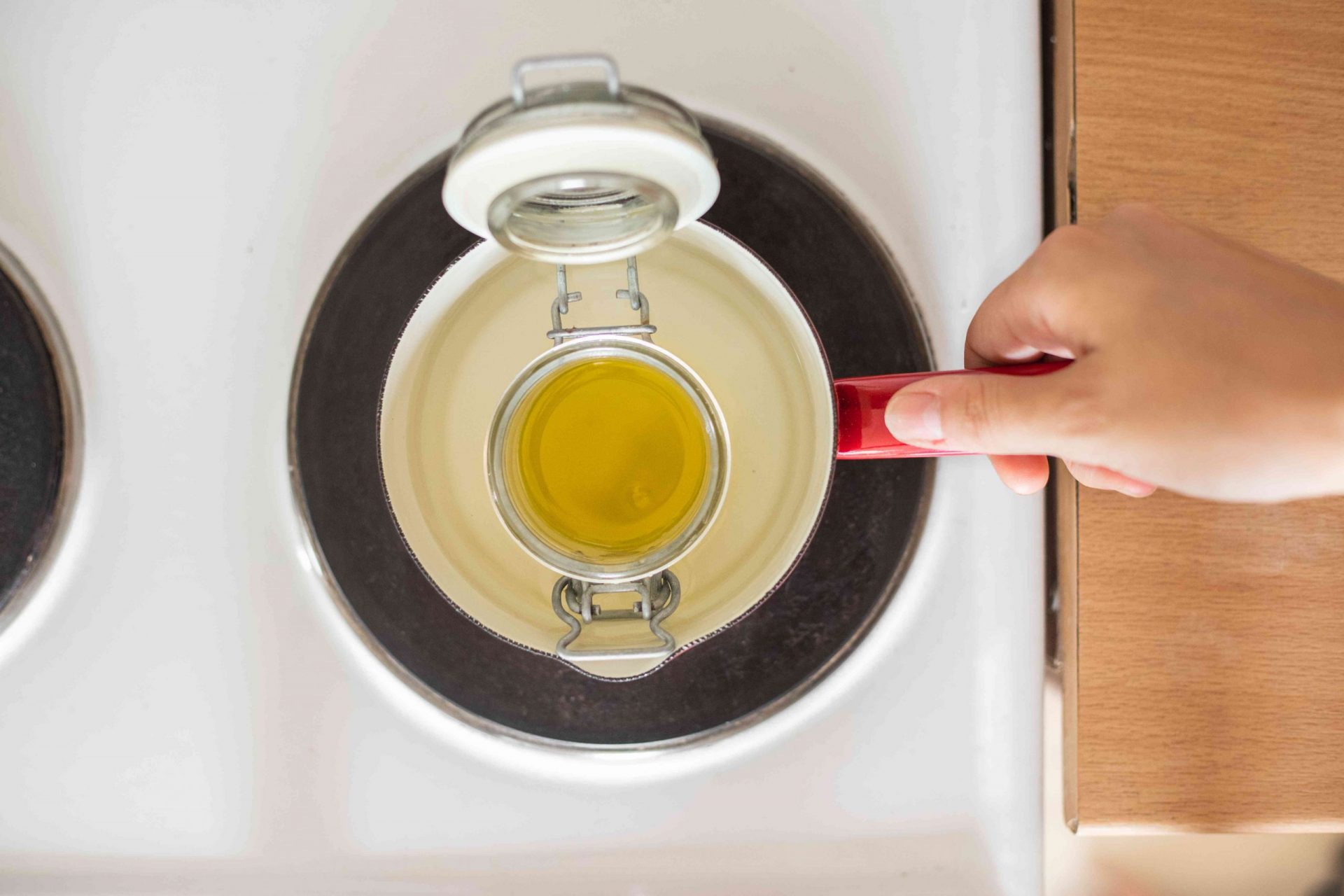 calienta a mano el aceite de oliva en un recipiente de cristal en la cocina eléctrica