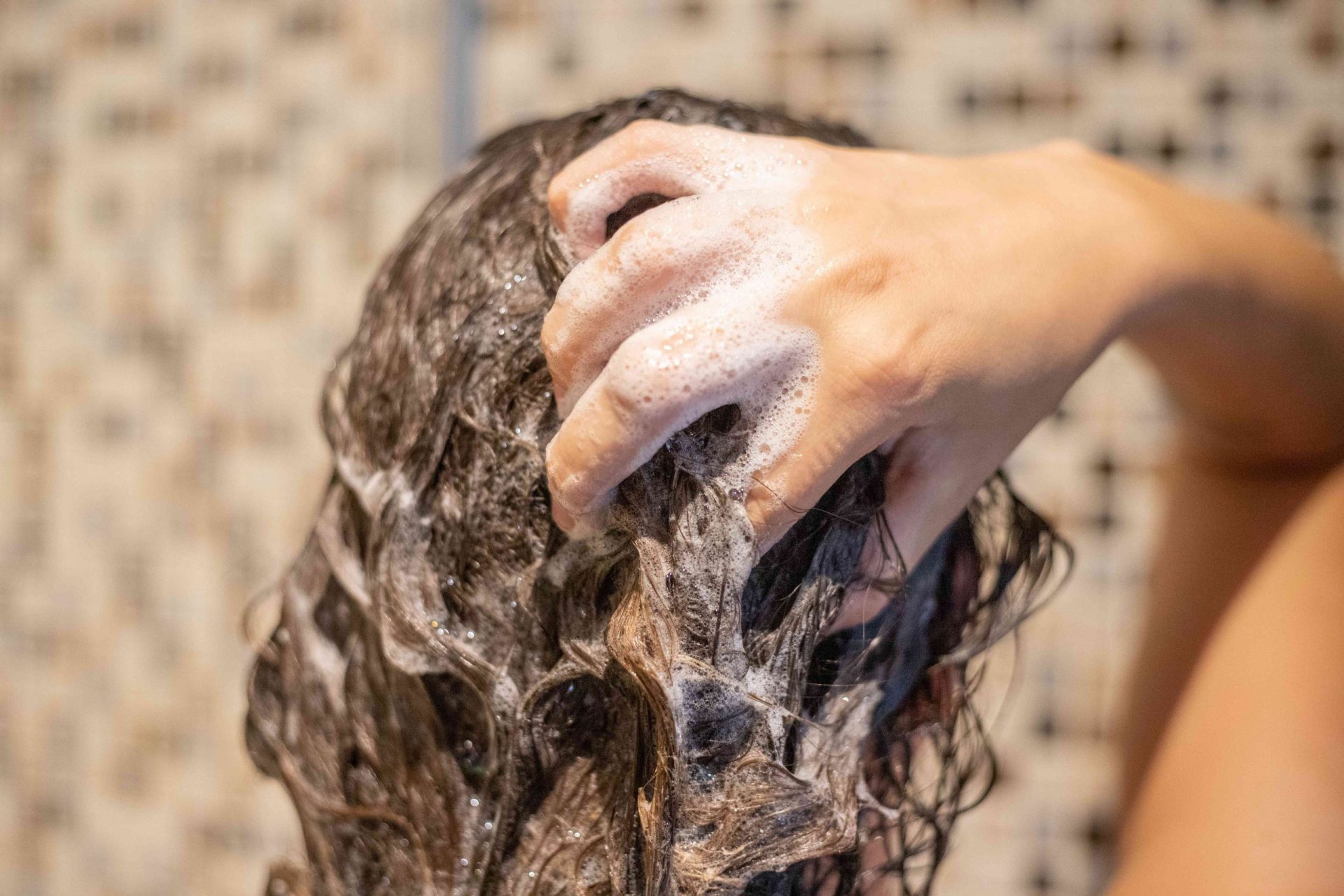 parte trasera de la cabeza de una mujer lavándose el pelo en la ducha