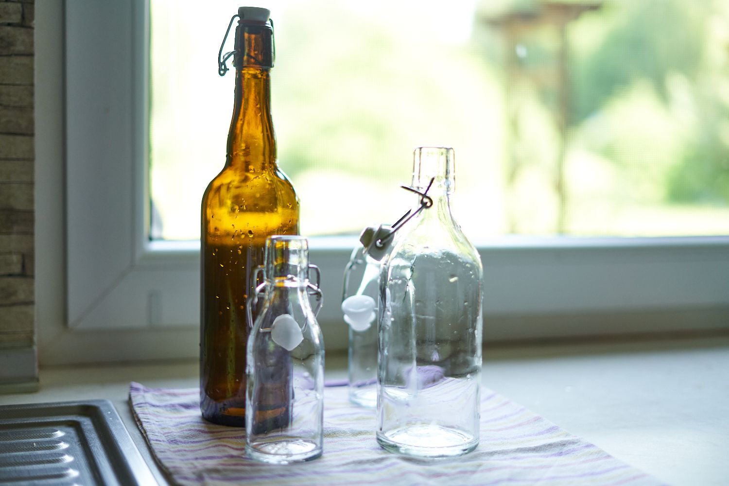 frascos de vidrio abatibles de varios tamaños recién limpiados junto al fregadero de la cocina