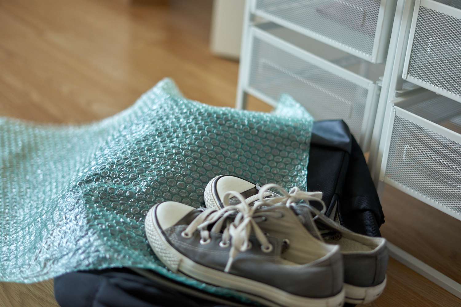 trozo usado de plástico de burbujas verde azulado con unas viejas zapatillas Converse y una mochila