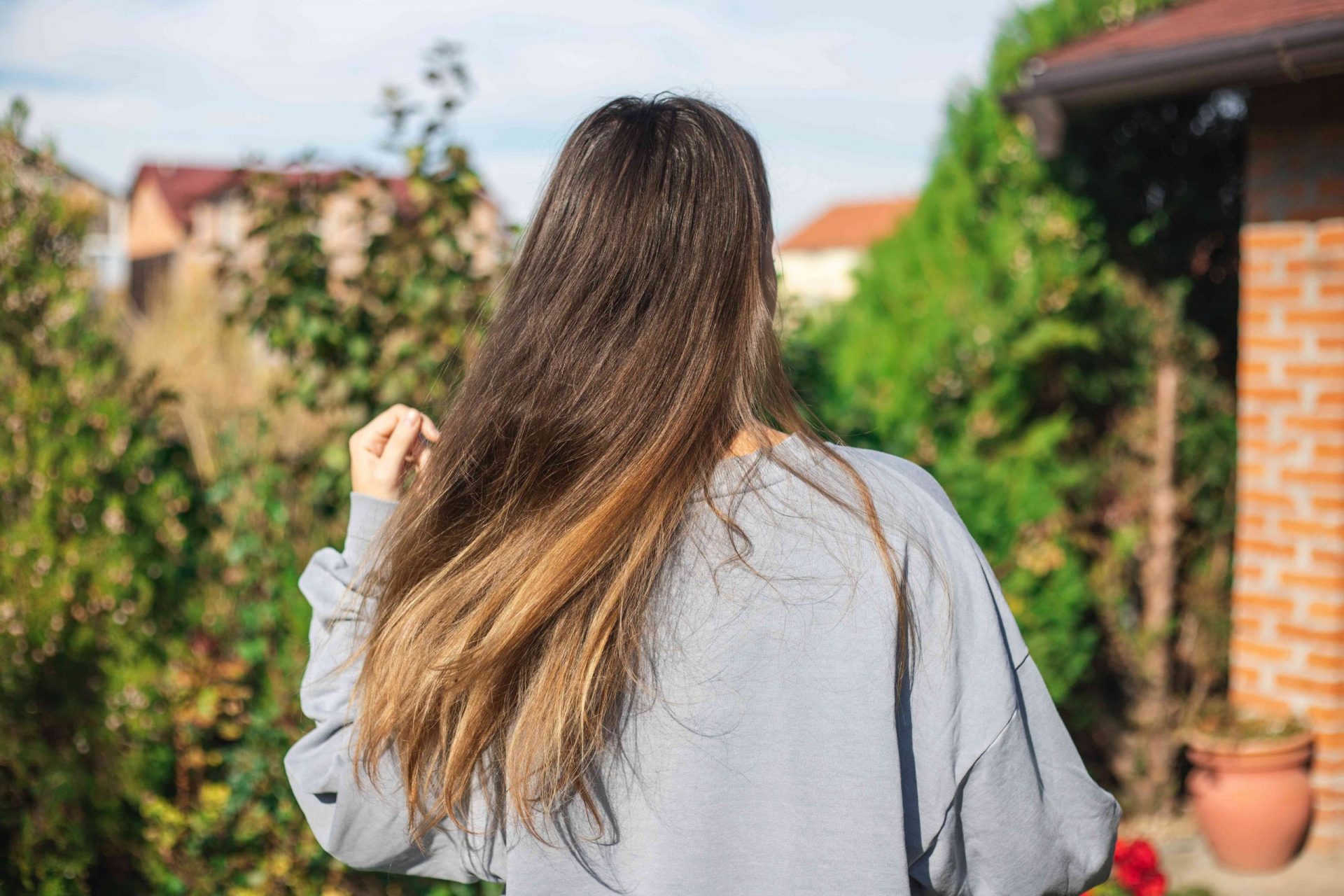 mujer con el pelo largo y brillante balancea el pelo al aire libre en el jardín