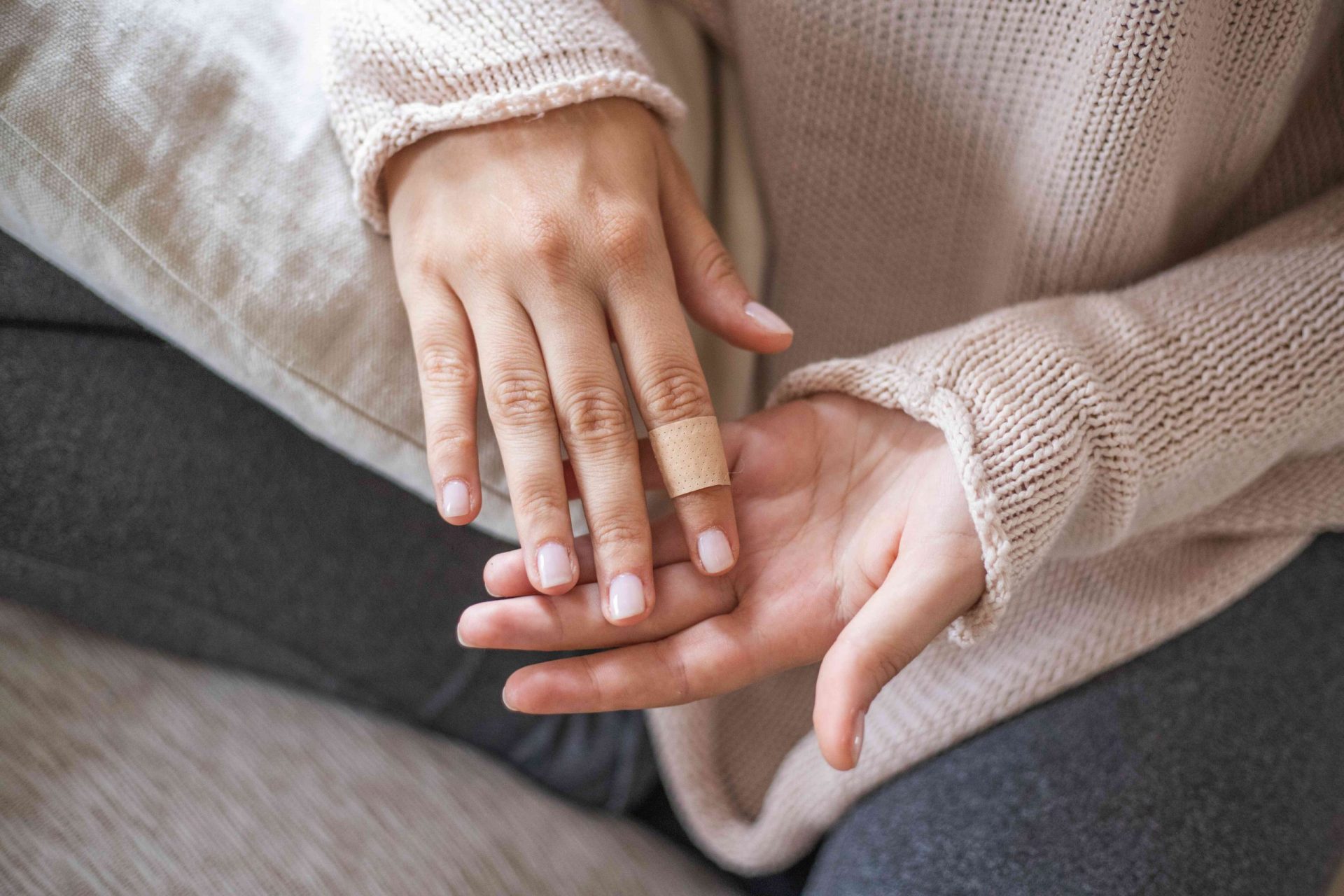 mujer con jersey rosa muestra el dedo con una tirita para connotar la cicatriz para la curación con aceite de lavanda