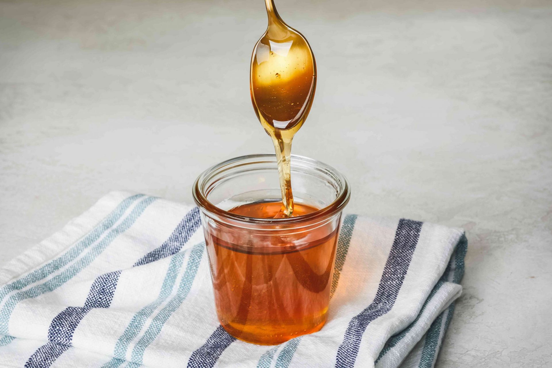 La cuchara dorada sumergida en un tarro de miel gotea al sacarla