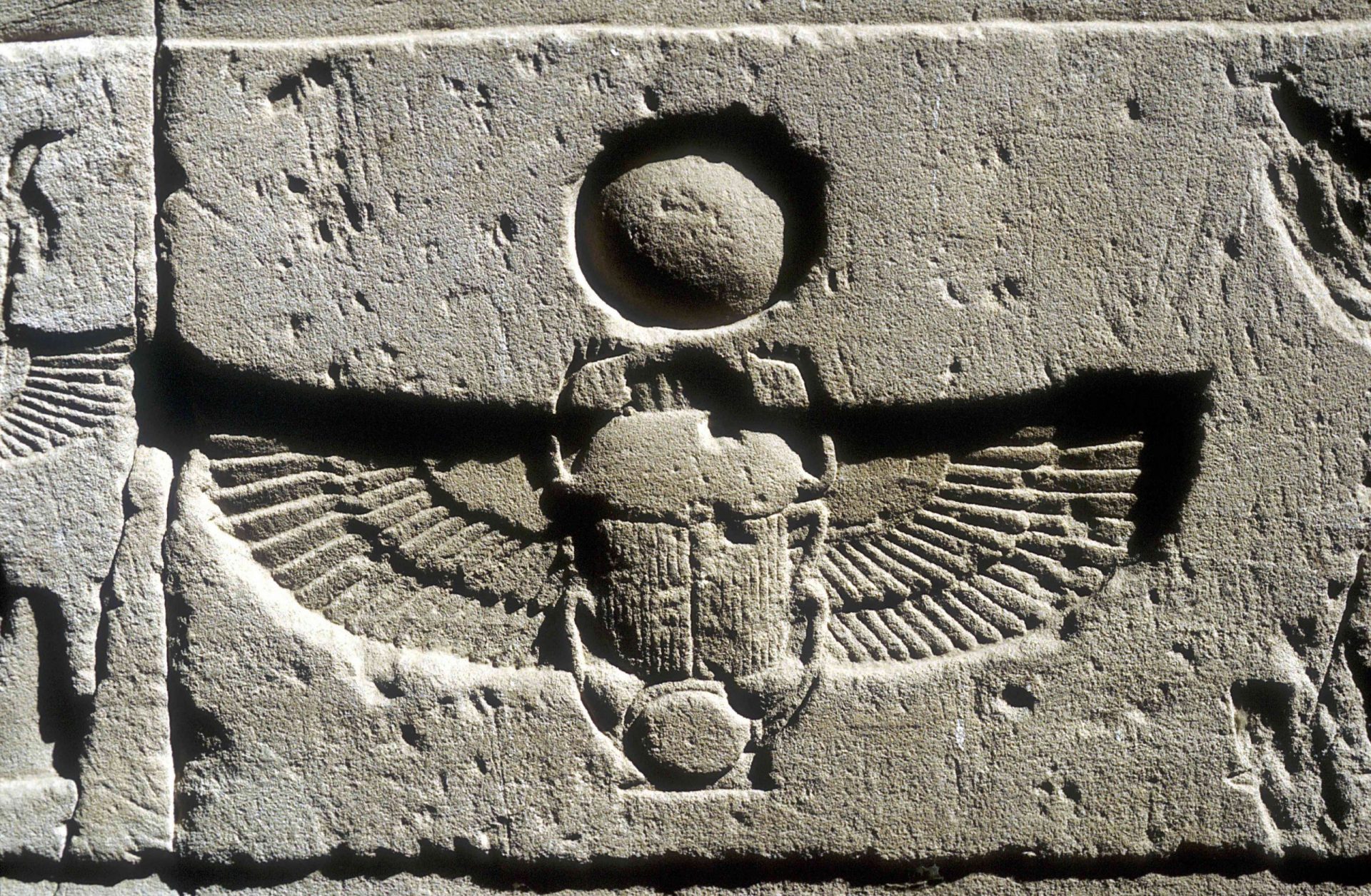 Relieve de piedra caliza de un escarabajo y alas de buitre bajo un disco de sol, Edfu, Egipto