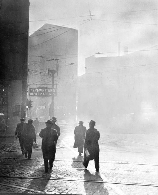 La gente camina entre la espesa contaminación y la niebla tóxica en la esquina de las avenidas Libertad y Quinta en Pittsburgh en 1940