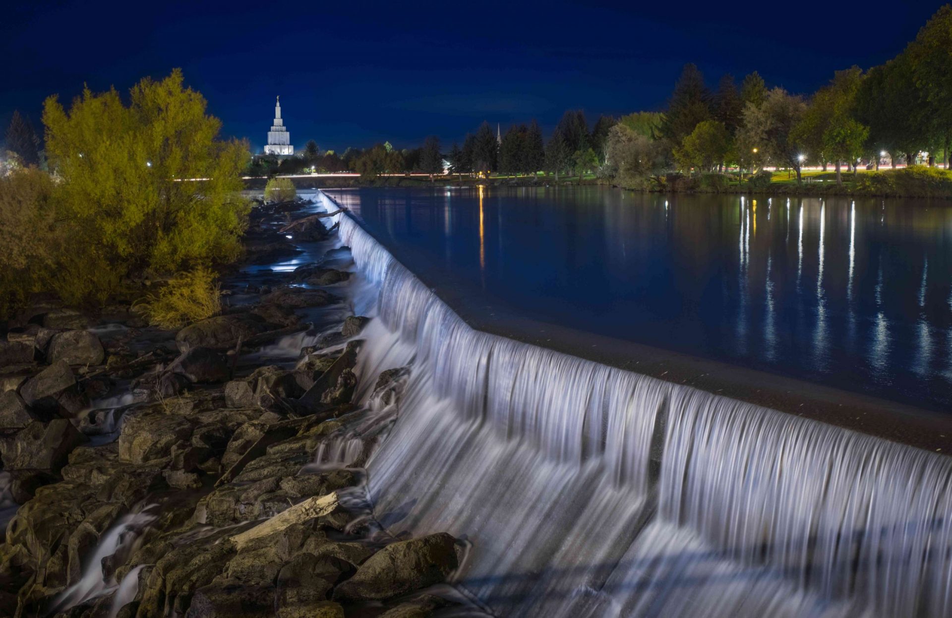 larga cascada de noche, con el agua cayendo desde un estanque azul sobre un lecho de rocas
