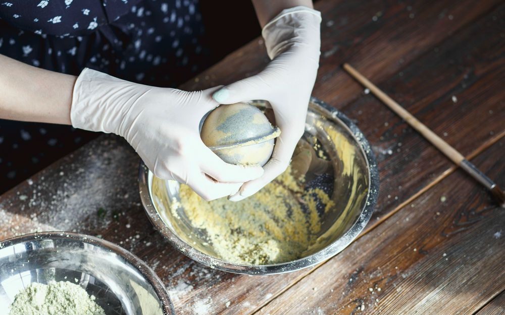 mujer presionando los ingredientes de la bomba de baño DIY en un molde redondo