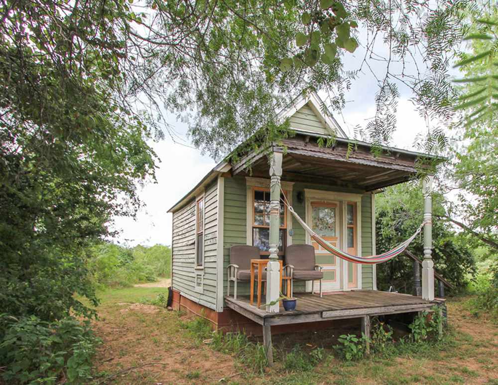 Casa diminuta verde en la naturaleza con hamaca en el porche