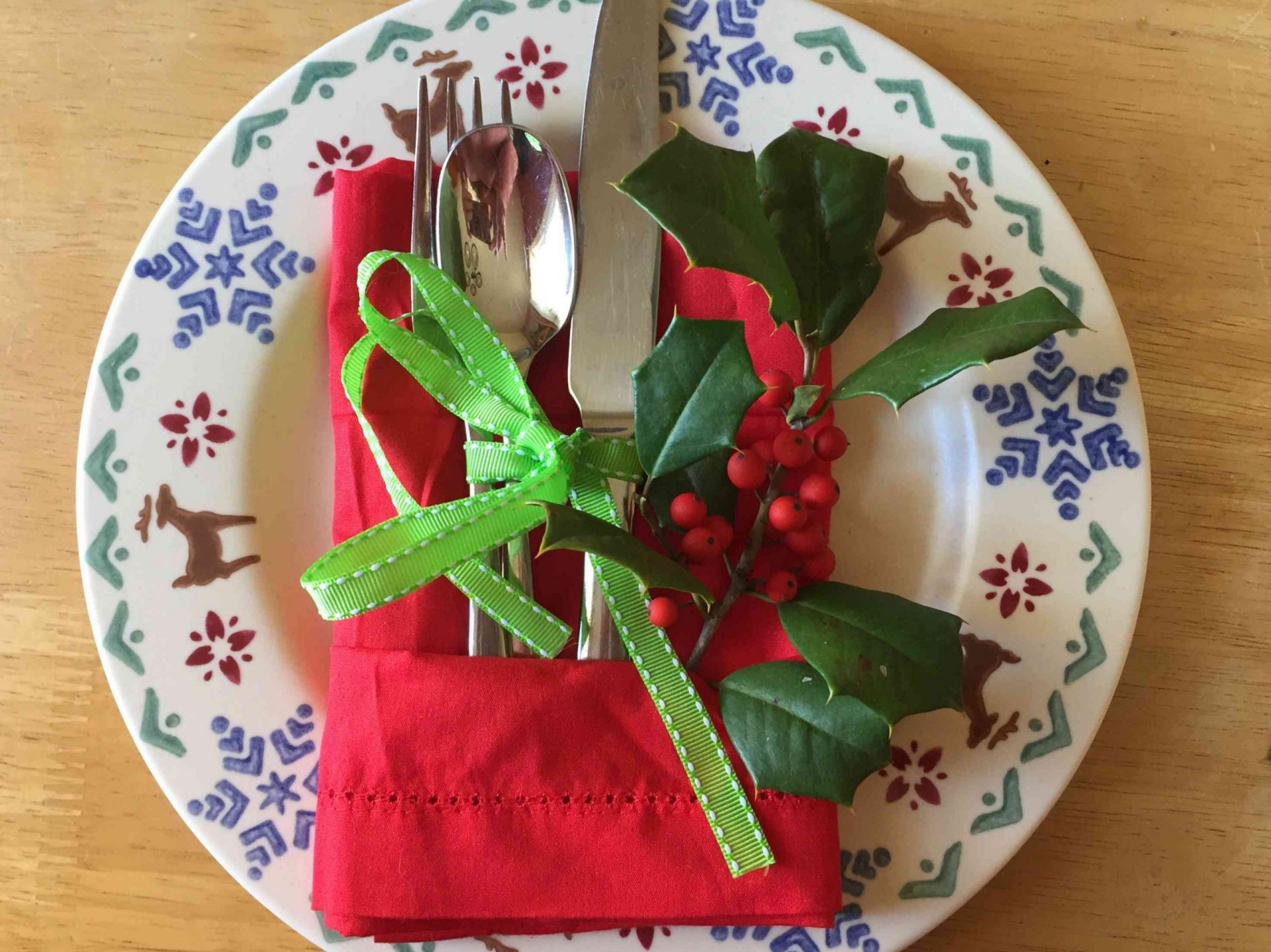 servilleta de tela roja doblada en forma de regalo para sujetar los cubiertos en el plato