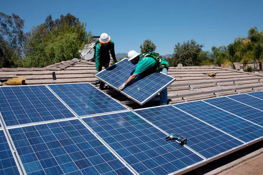 Dos trabajadores instalan paneles solares en una casa de Oak View, en el sur de California