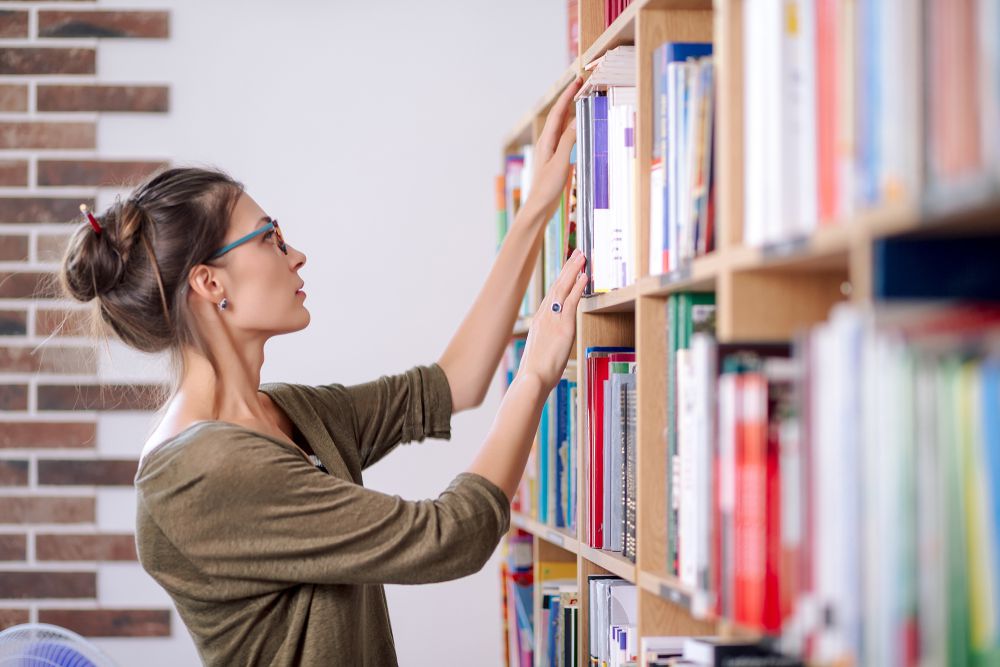 mujer eligiendo libros en la biblioteca