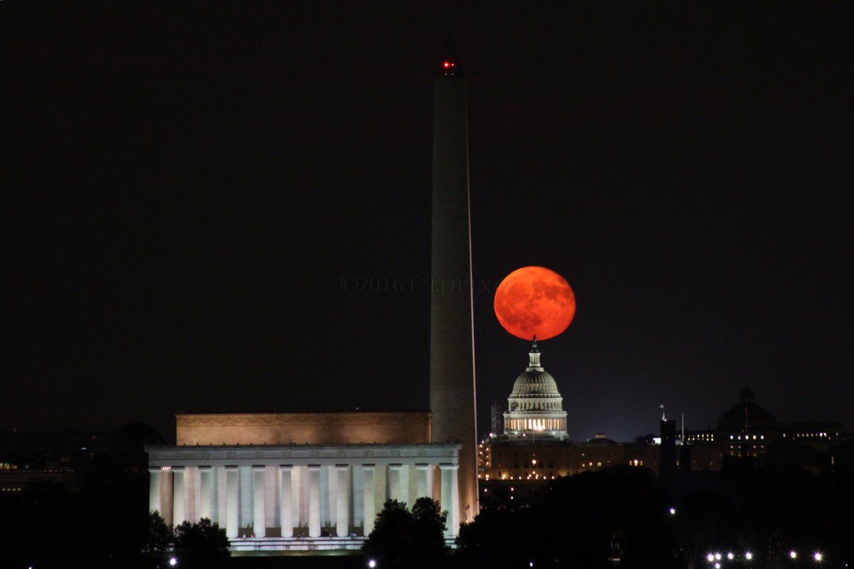 una luna llena y anaranjada aparece sobre el horizonte de DC