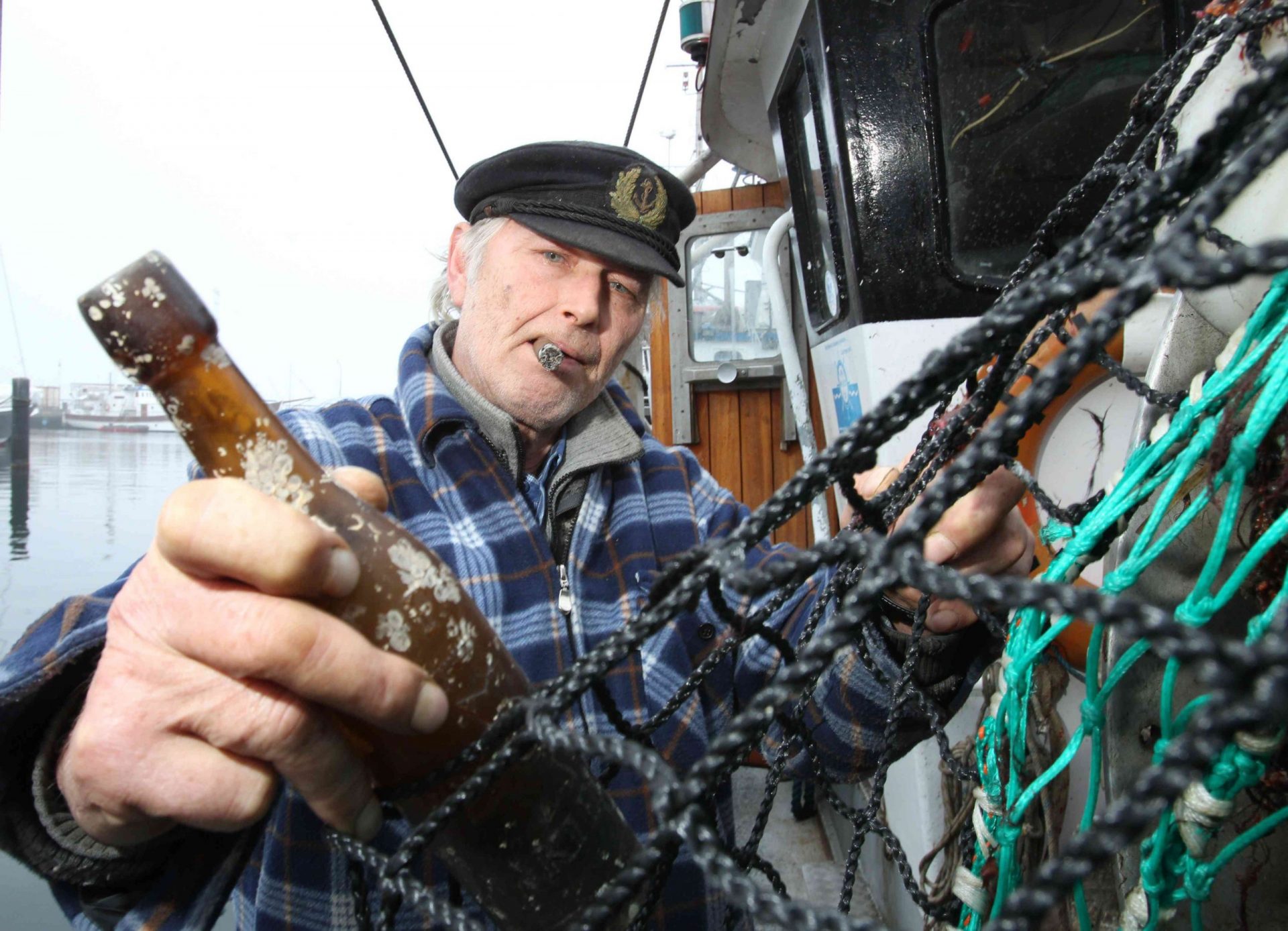 Pescador sacando una vieja botella de la red de pesca