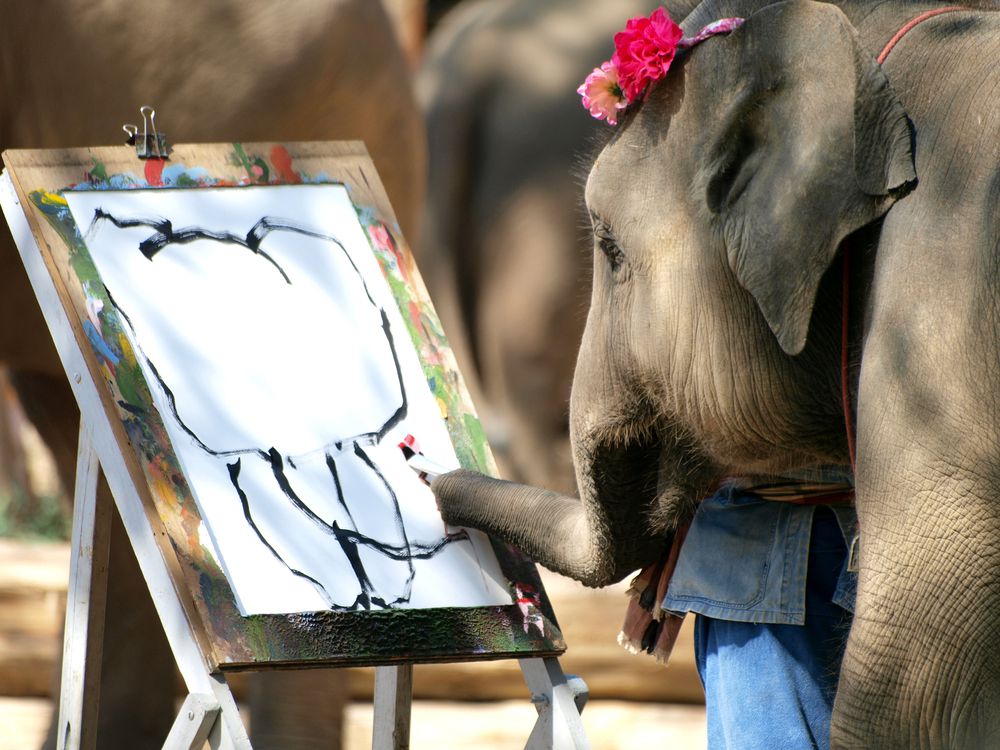 un elefante sosteniendo un pincel con su nariz, pintando un cuadro de un elefante