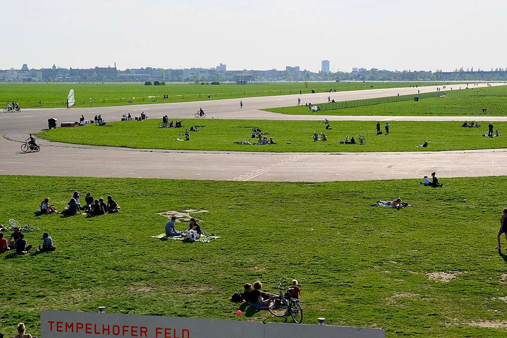 Los visitantes del parque se sientan en los verdes campos del antiguo aeropuerto de Tempelhof en Berlín