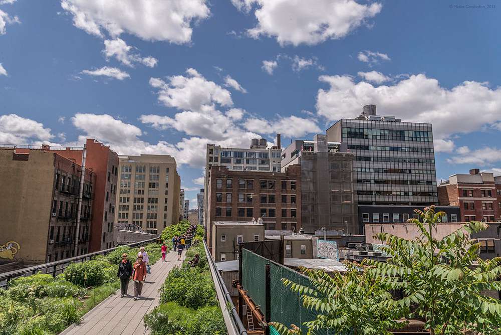 Los peatones caminan por el High Line con el paisaje urbano de fondo