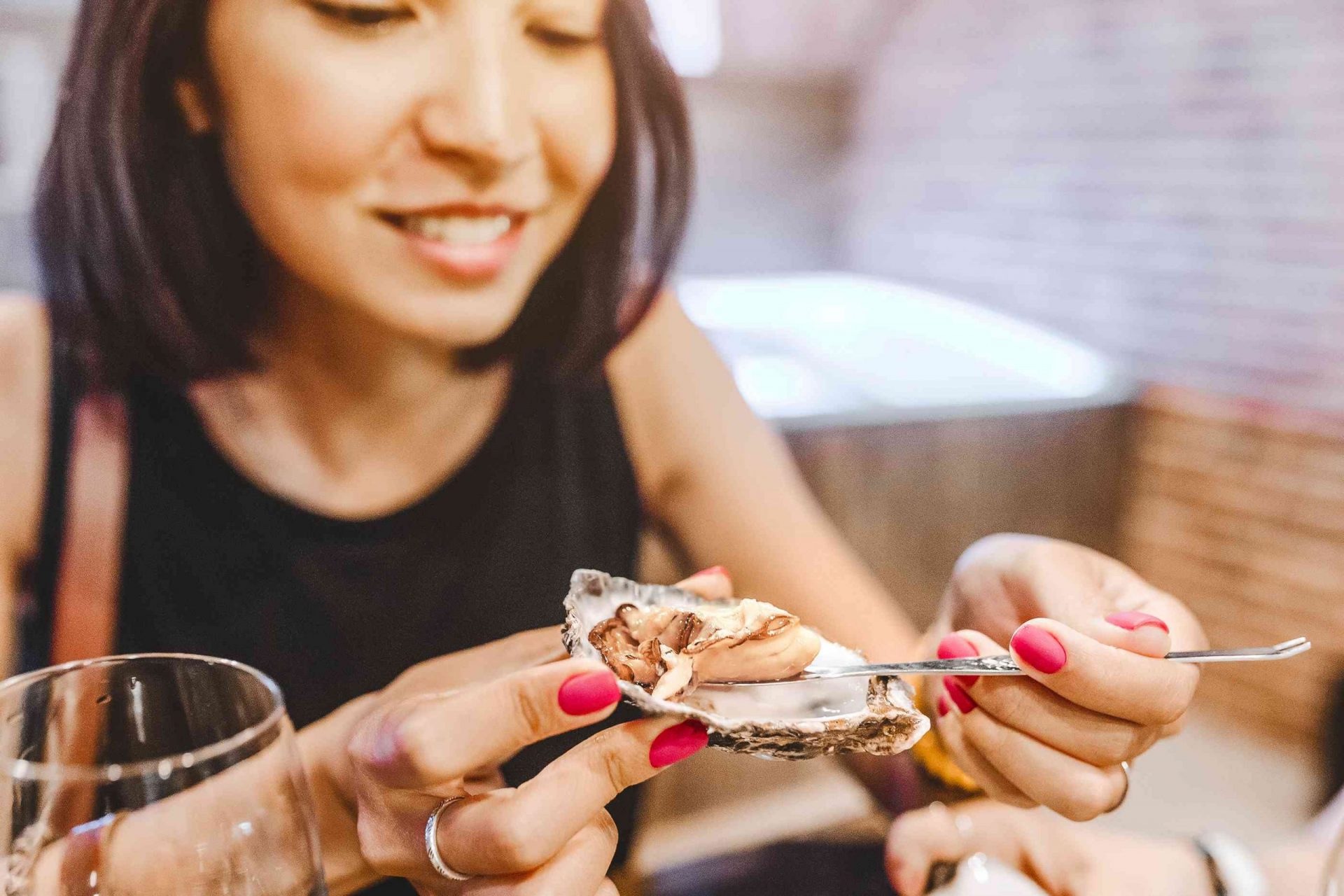 primer plano de una mujer comiendo una ostra fuera de su concha con una cuchara