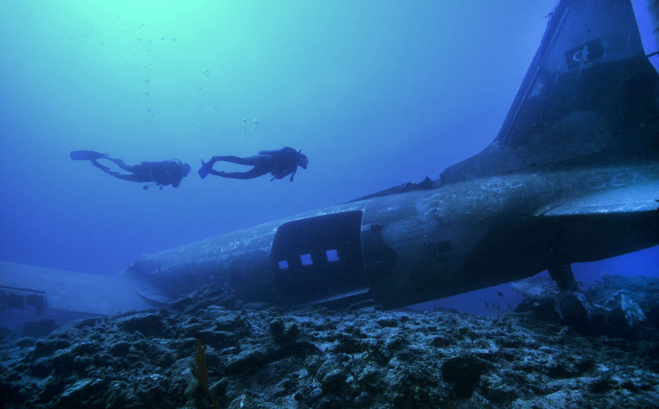 Dos submarinistas exploran los restos de un avión en el fondo del océano