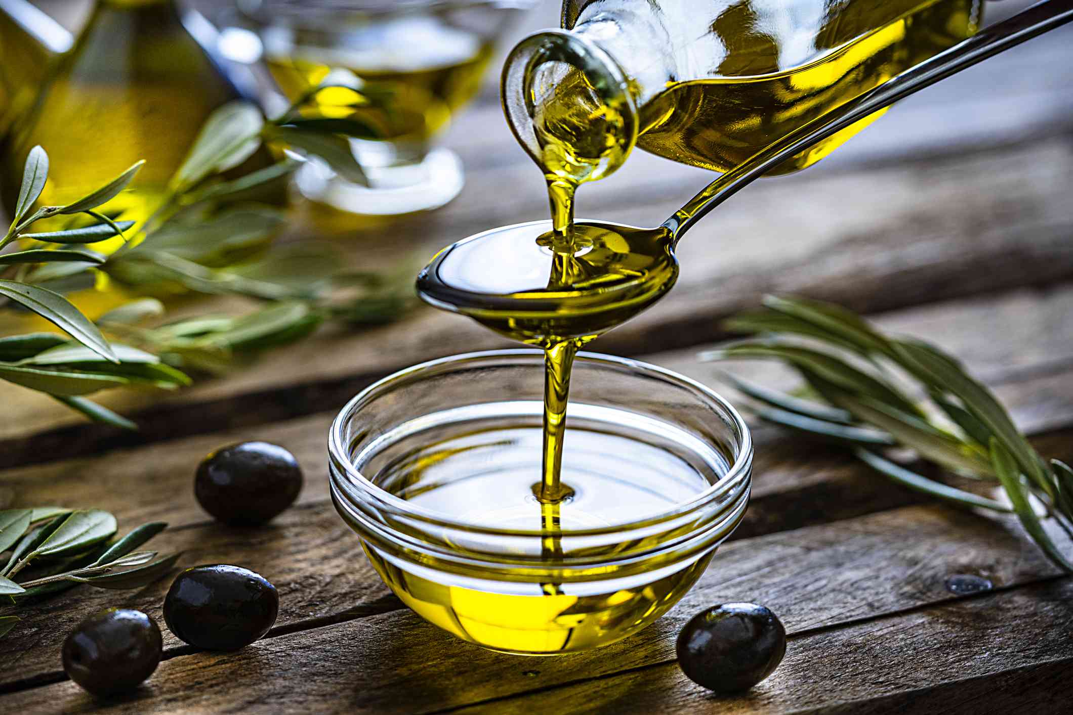 Vertiendo aceite de oliva virgen extra en un recipiente de cristal