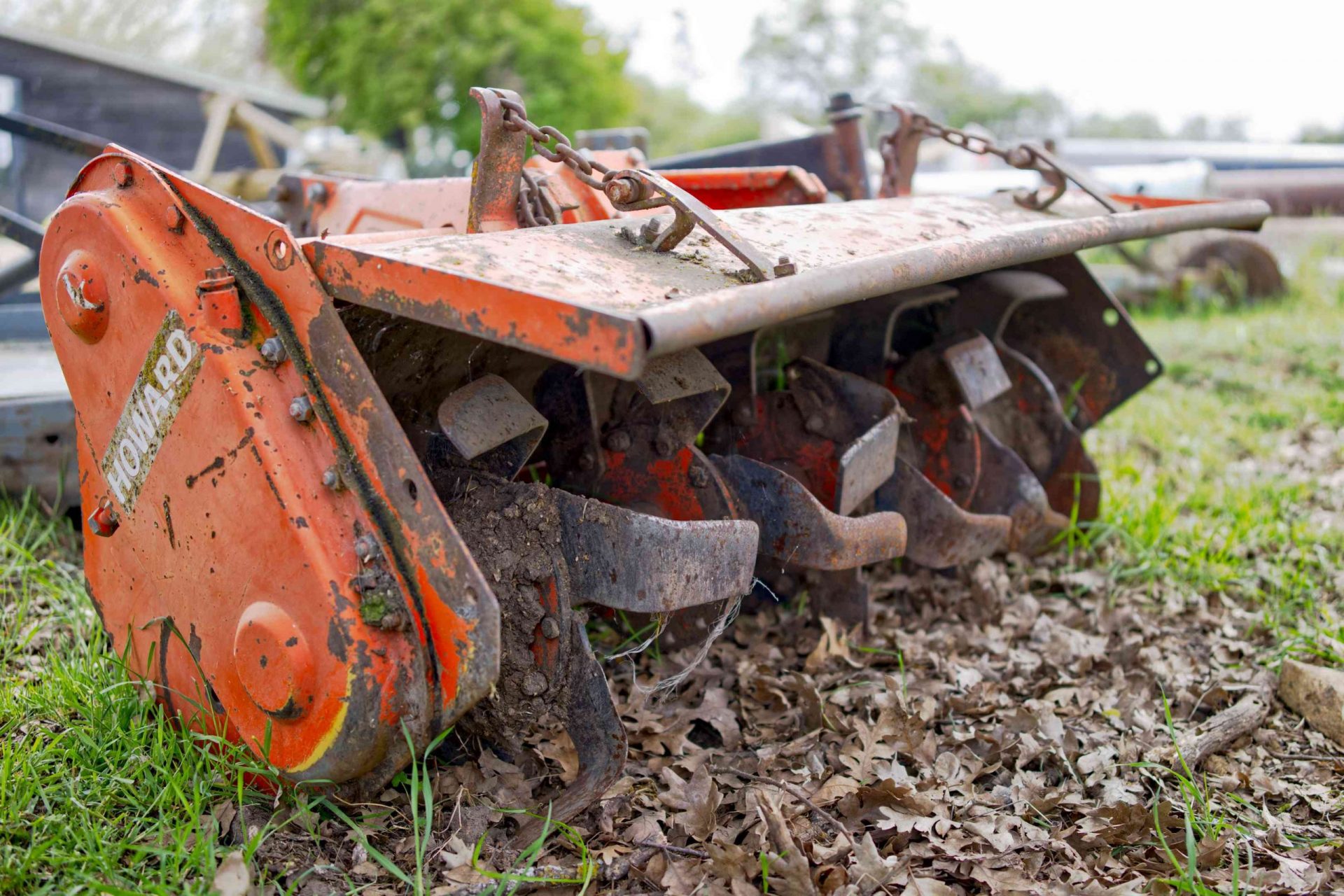 foto de cerca de un equipo agrícola de toma de fuerza metálica naranja rompiendo la tierra