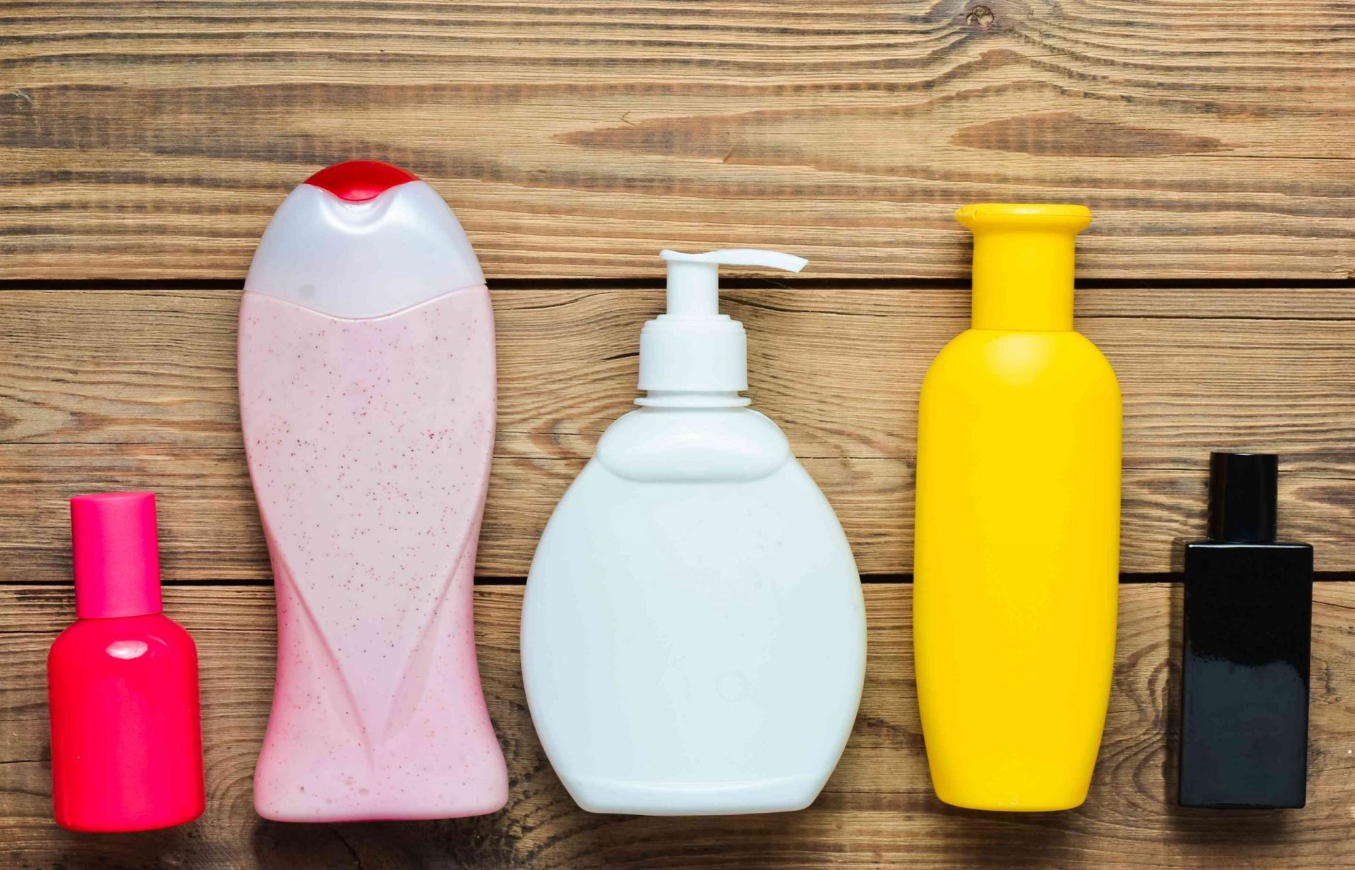 Productos para la ducha en botellas y frascos de perfume sobre una mesa de madera. Cuidado personal. Objetos para la higiene y la belleza. Vista superior. Flat lay