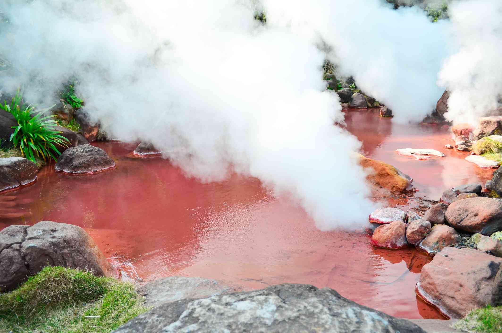 estanque de sangre en Beppu, Japón, con un espeso vapor que surge del agua de color rojo brillante