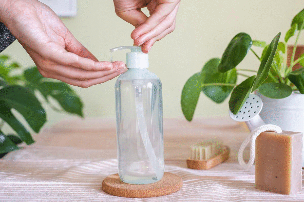 manos exprimiendo el gel limpiador transparente del frasco con bomba en las manos