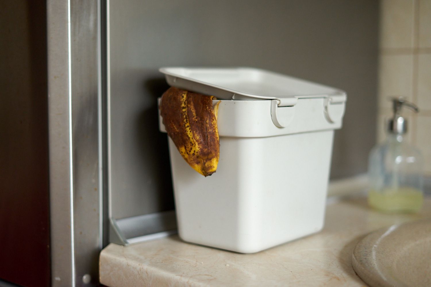 cáscara de plátano marrón usada en el cubo de compostaje blanco de la cocina