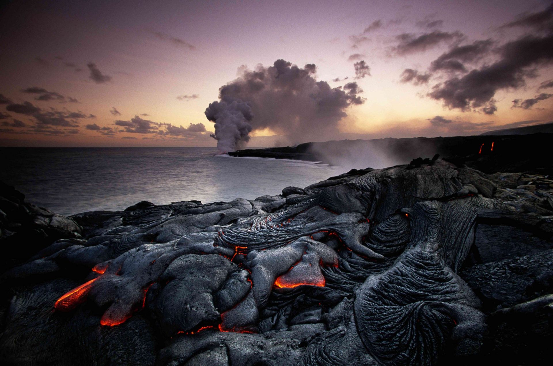 Lava con el Kilauea en erupción al fondo en el Parque Nacional de los Volcanes