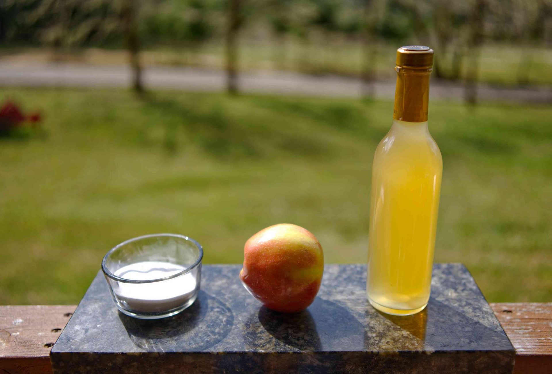 Bicarbonato de sodio en un tarro de cristal y vinagre de sidra de manzana expuestos en una tabla de cortar de mármol