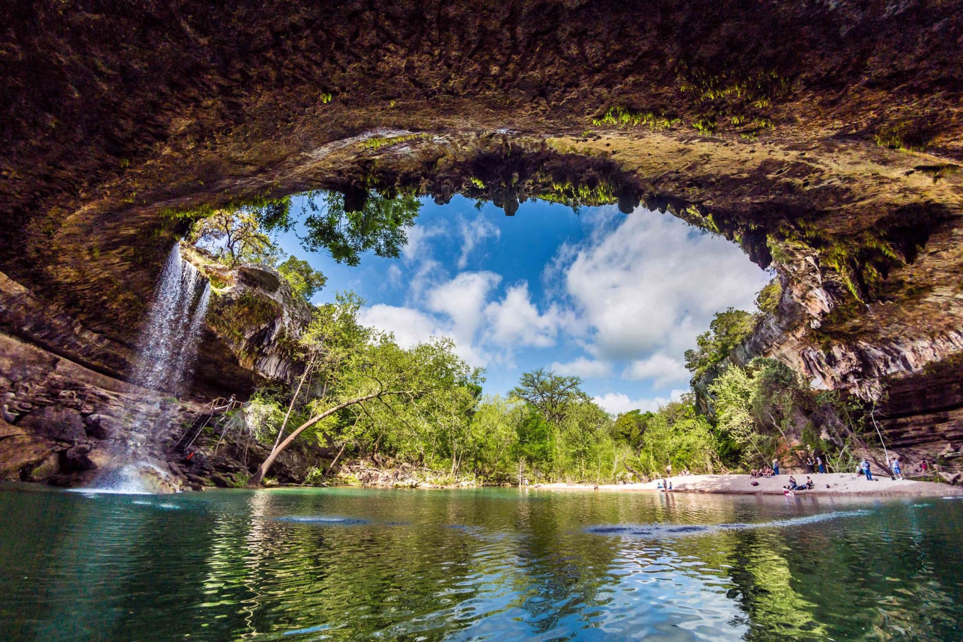 La gruta que parece una caverna en la Reserva de la Piscina Hamilton, con una cascada que fluye hacia abajo, se abre a un brillante cielo de verano