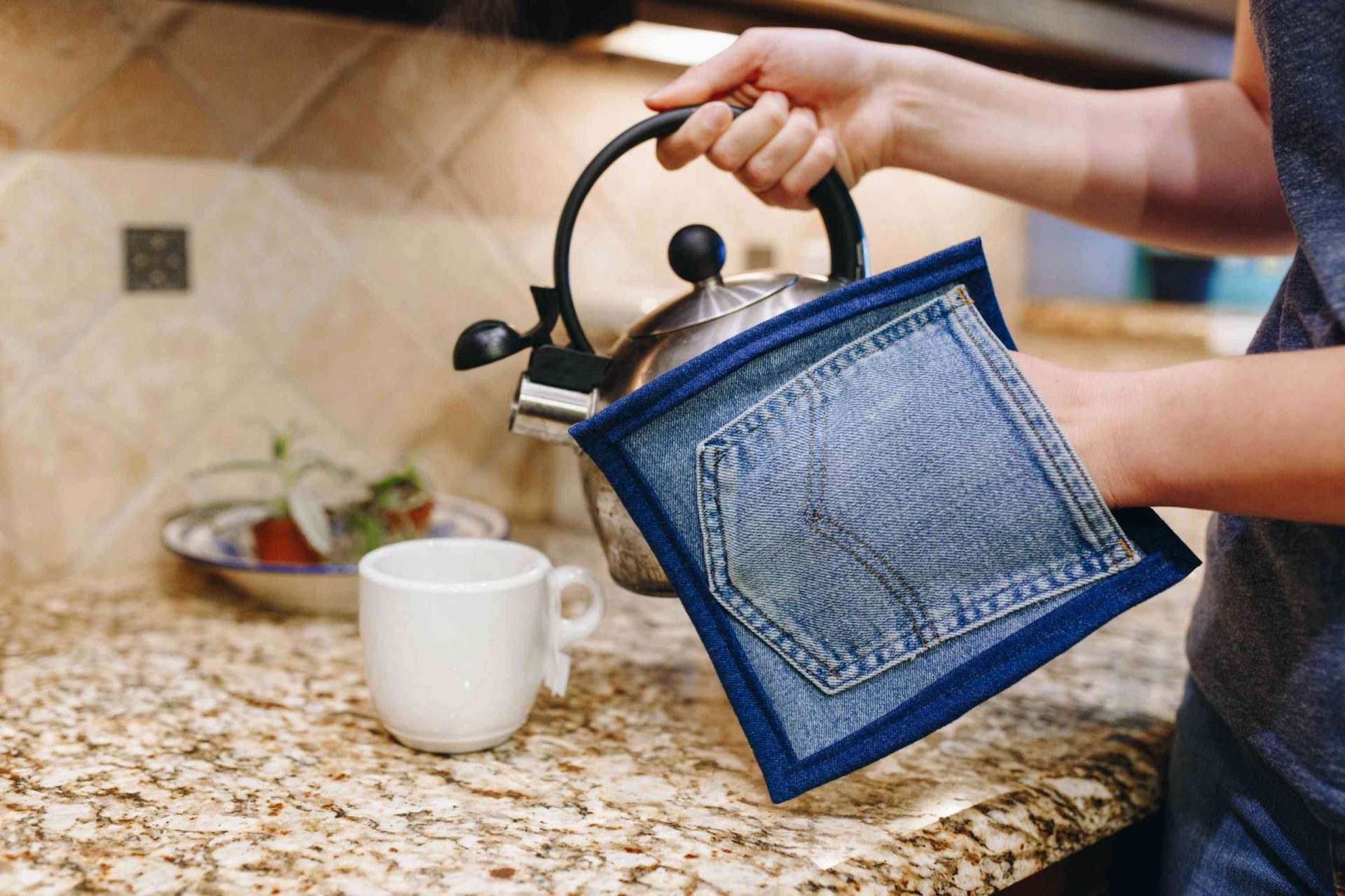 una modelo en la cocina utiliza una agarradera vaquera reciclada para verter agua caliente