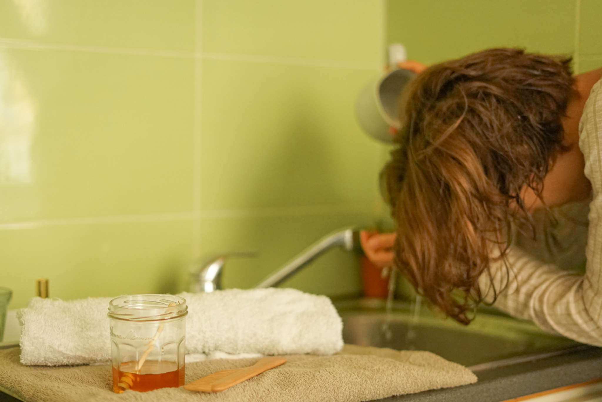 la mujer se inclina sobre el fregadero de la cocina y se lava el pelo con miel