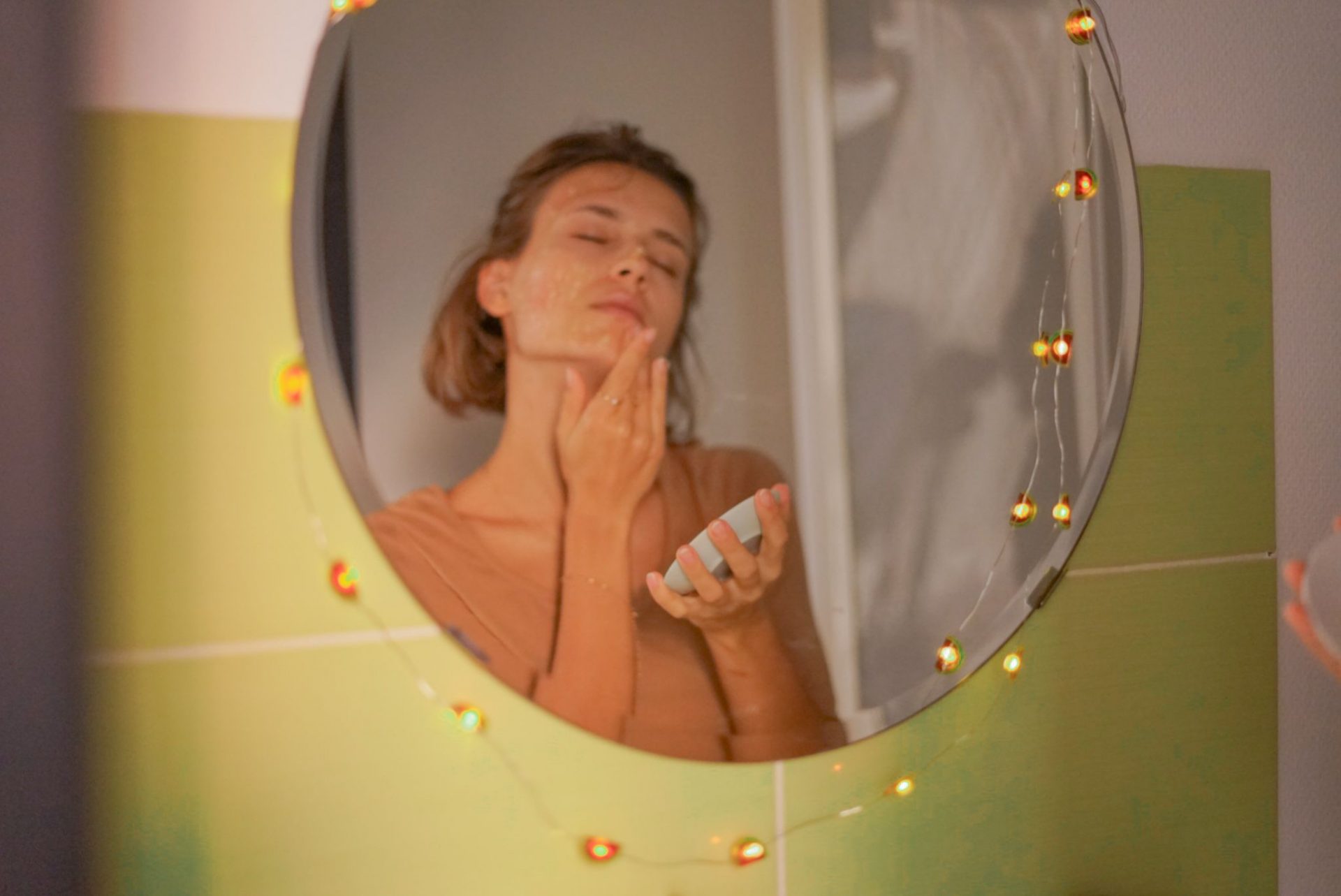 reflejo en el espejo de una mujer en el cuarto de baño frotando miel en la cara para un tratamiento de belleza natural