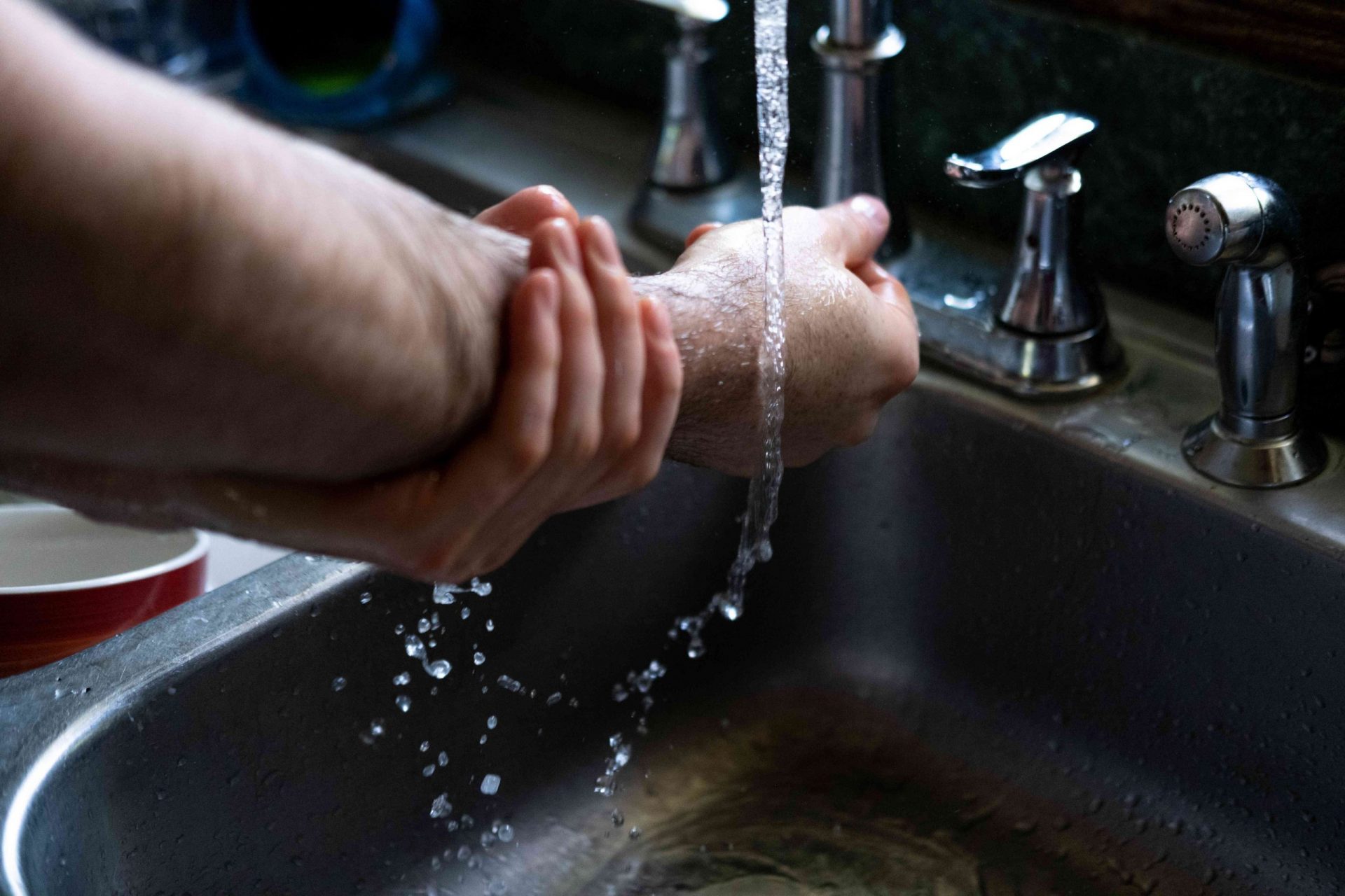 manos y brazos se limpian en profundidad con agua corriente en el fregadero de la cocina